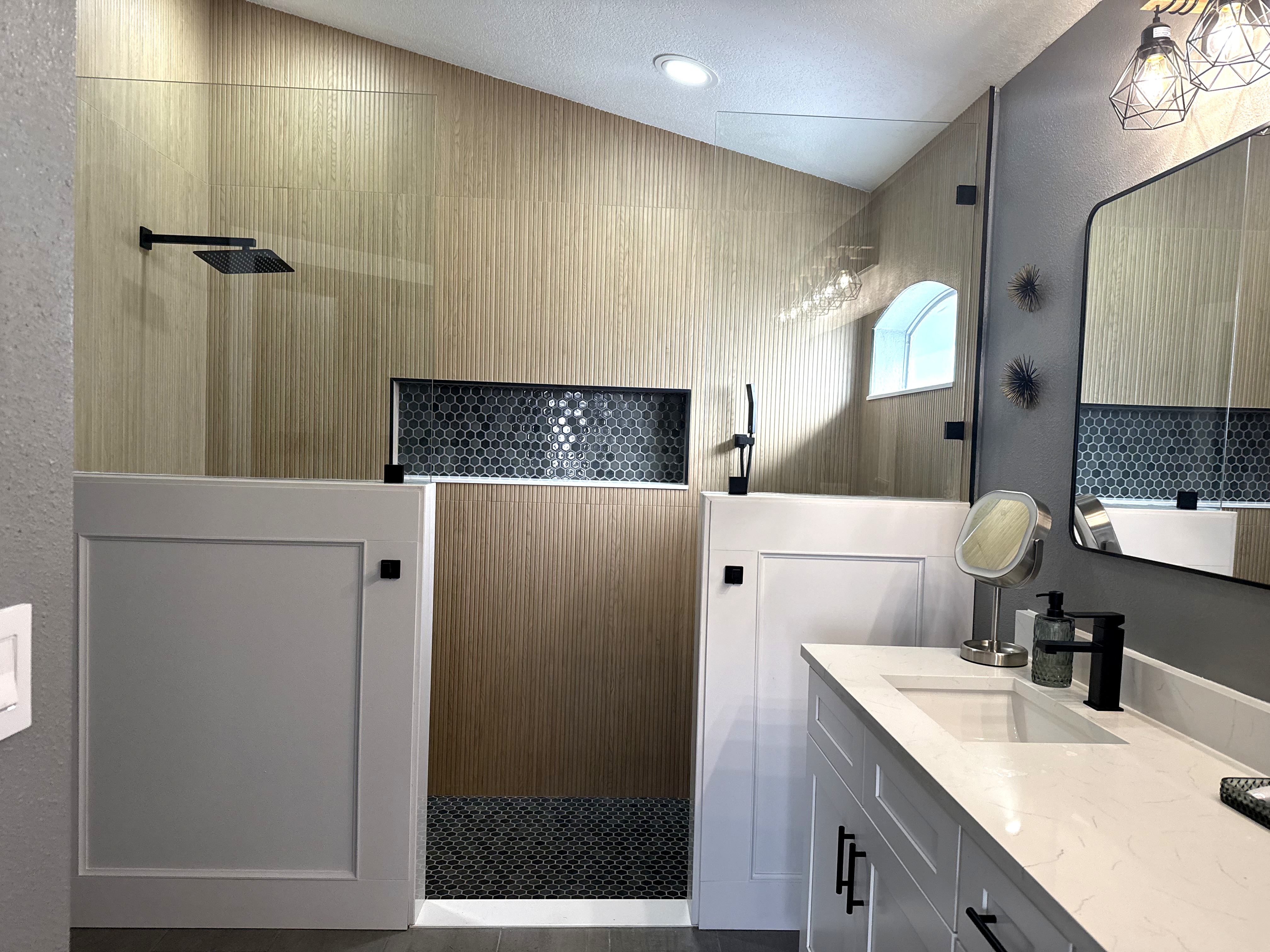 Modern master bath with fluted wood wall, hex tile, and matte black fixtures